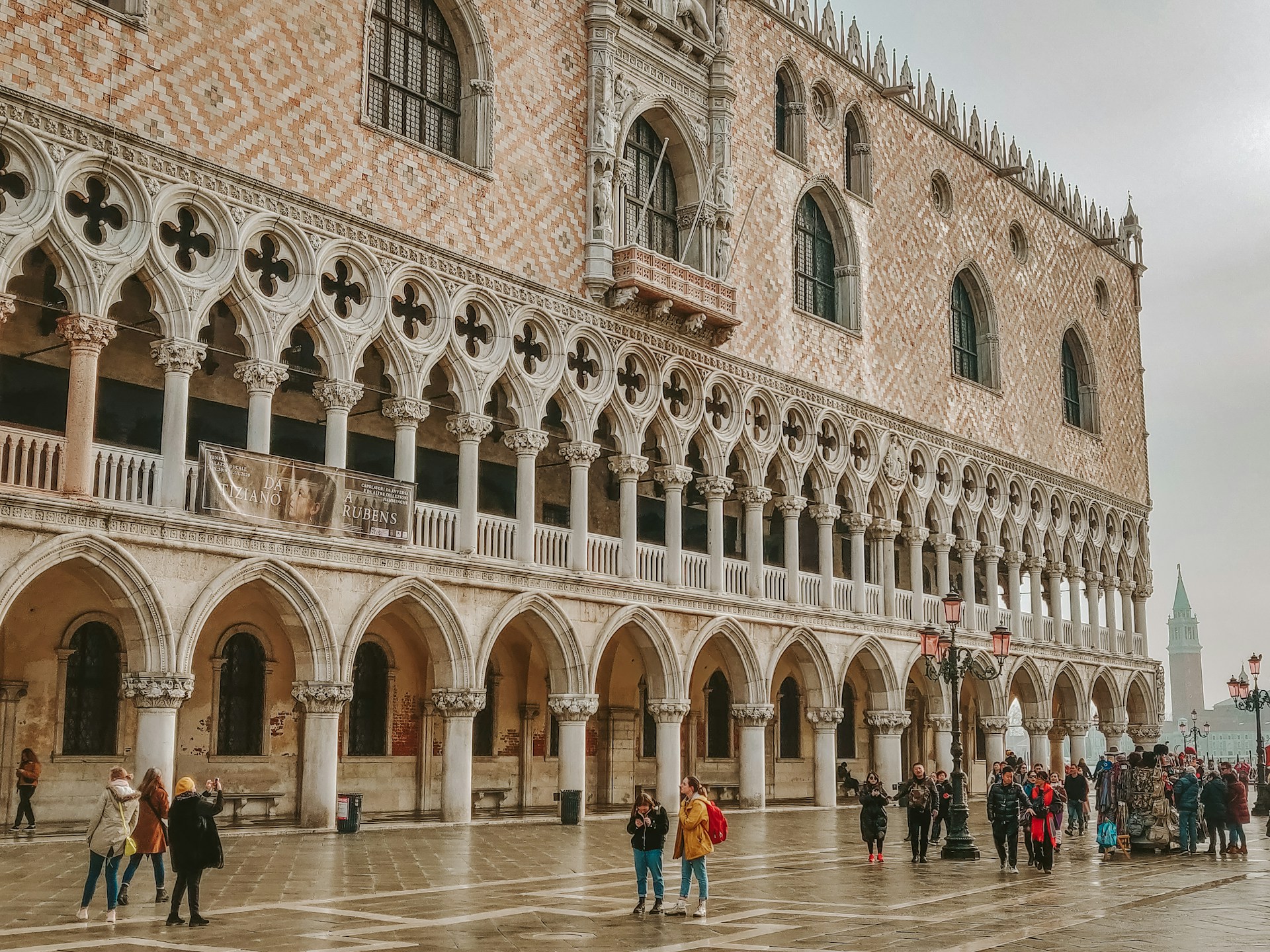 The Gothic arcades and pink-and-white patterned facade of the Doge's Palace on a misty day